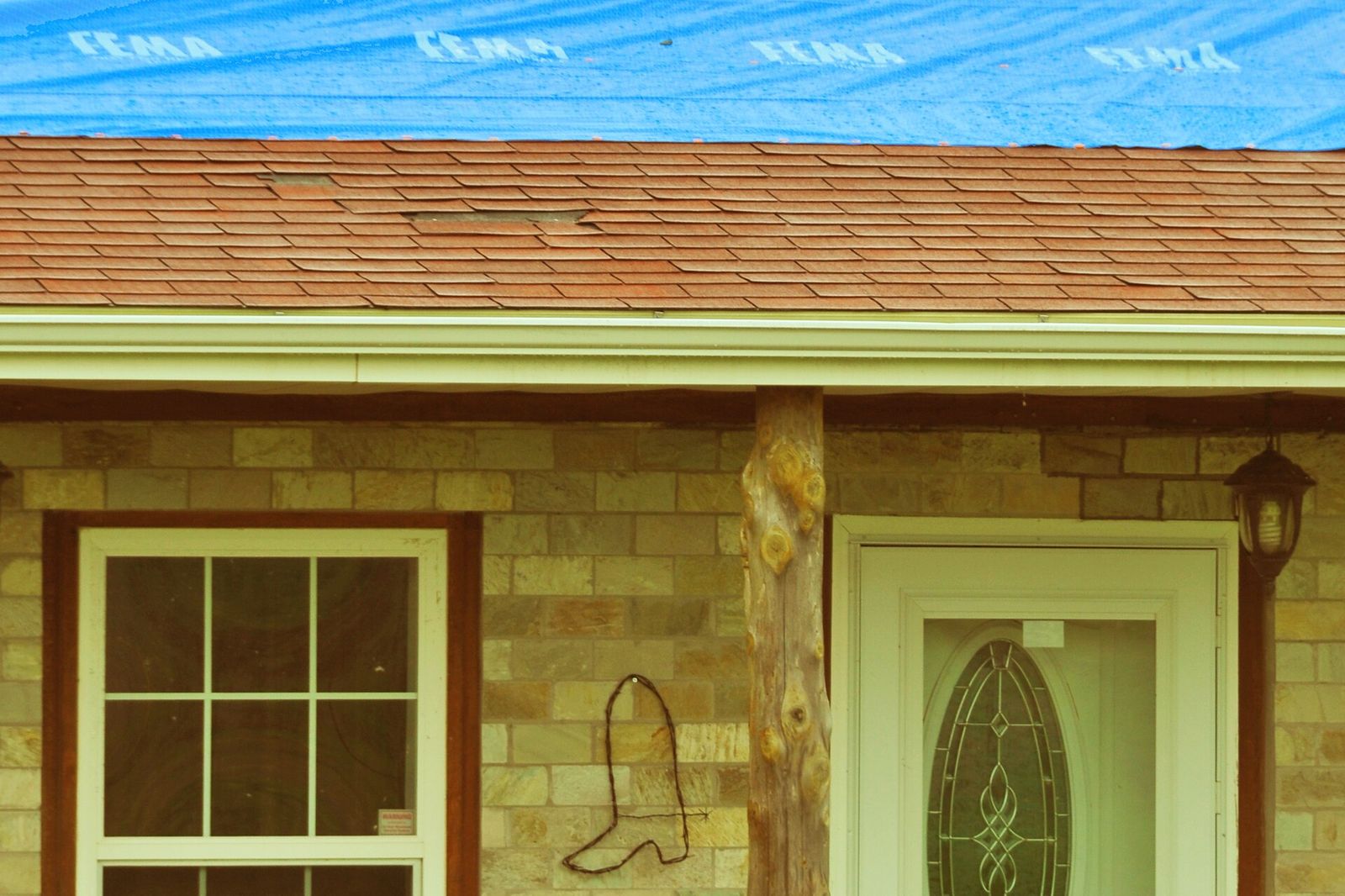 Blue tarp fastened over a damaged roof